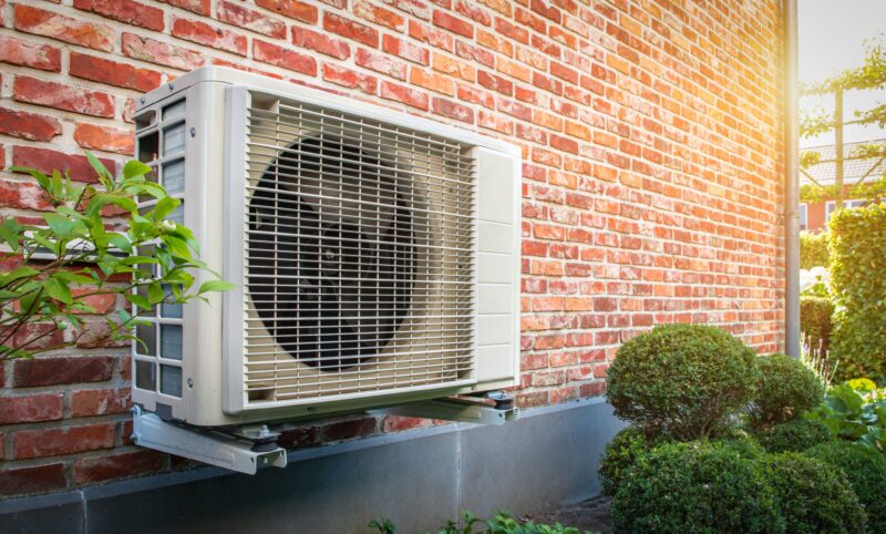 heat pump mounted on the brick wall of a home