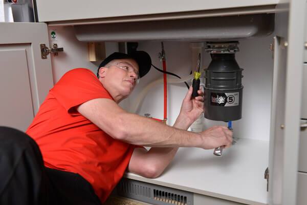 Plumber repairing a home's garbage disposal