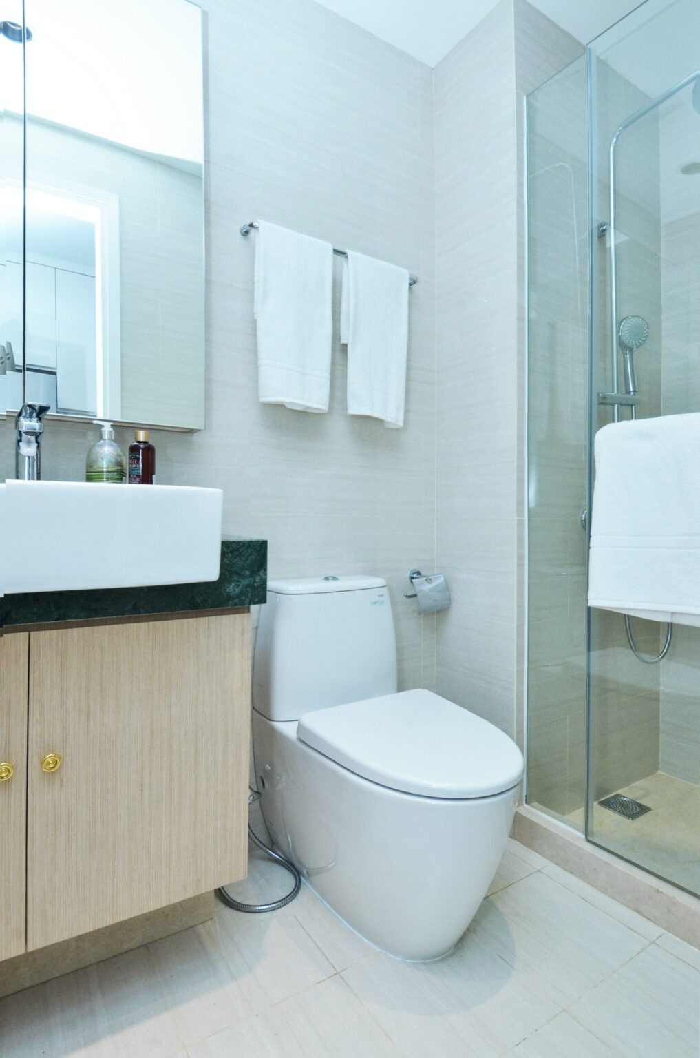 Newly renovated bathroom with white toilet, sink & walk-in shower